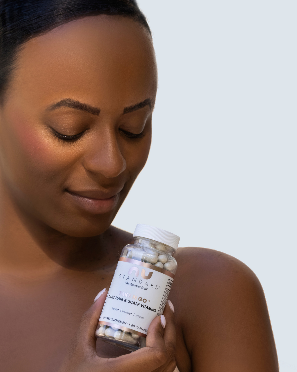 Woman holding bottle of TAKE N GO™ Daily Hair & Scalp Vitamins
